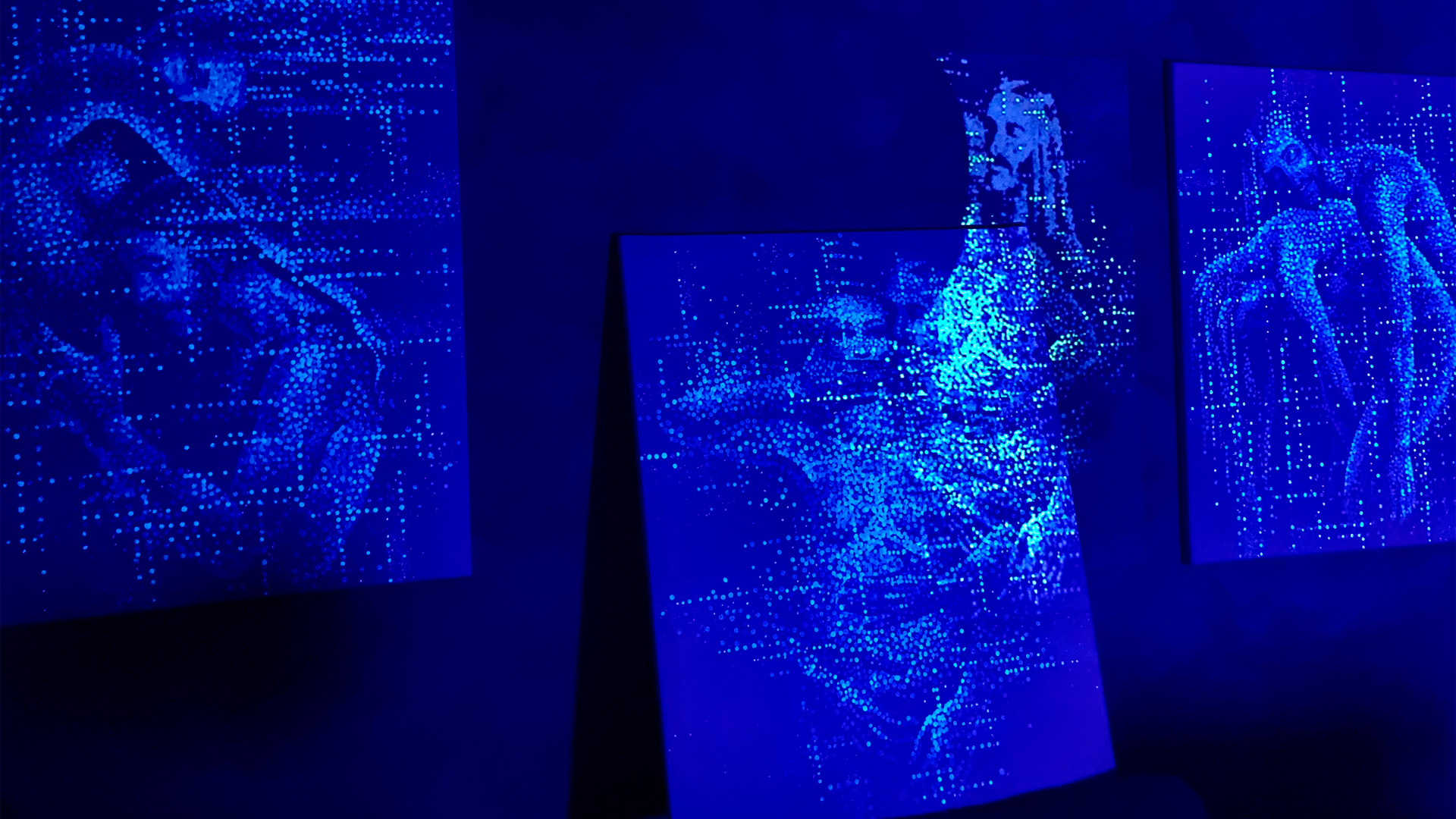 triptych of paitnings visible ponly under uv lights, with projected imaged on top.